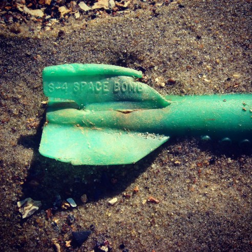 Howard Warren and his students research the waste at Deadhorse Bay, and have dated most of the waste escaping the landfill as circa 1930s. One of the dating methods is identifying objects like this. Plastics were introduced as consumer items on either side of World War II, and they can use the serial number on this plastic toy missile to identify when it was manufactured, and thus when it was probably disposed of. Photography by Max Liboiron. 