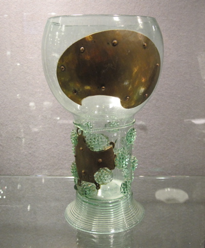 Two brass palette-shaped plates, convex on the outside and concave on the inside, have been riveted together to conceal a large hole in the center. From Past Imperfect. 