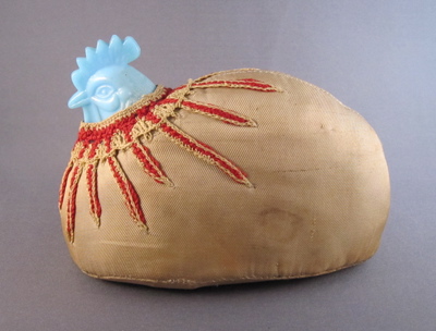 Milk glass hen pin cushion, c.1890. This  “make-do” pin cushion is made from a broken lid. "I assume the intact bottom half was reused as a dish, but the top half remains were encased in fabric and cotton batting, crocheted with red “feathers” around the neck and transformed in to a practical pin cushion."