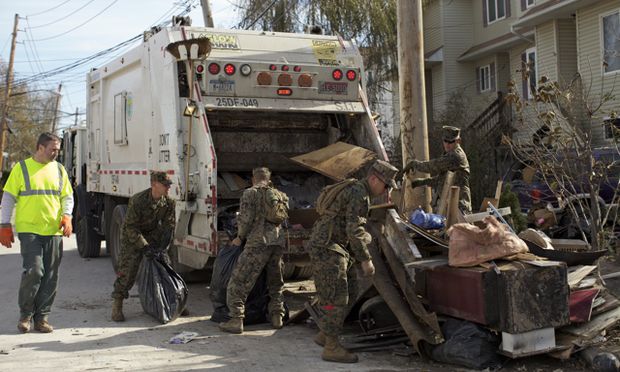 A sanitation worker teams up with members of the National Guard to clear debris in the Midland Beach section of Staten Island. (Amy Pearl/WNYC) 
