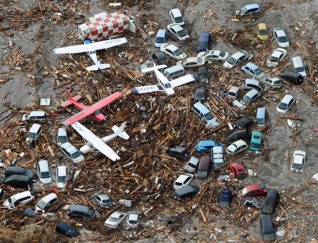 Light planes and vehicles sit among the debris after they were swept by a tsunami that struck Sendai airport in northern Japan on Friday March 11, 2011. Image by By Kansan Staff.