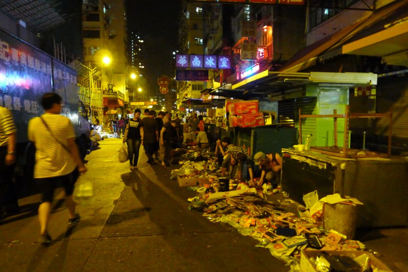 Image 3: Sellers of second-hand goods set up in front of the closed street stalls as pedestrians and cars pass by (photo courtesy of author).