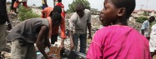 A group of boys and young men work on disassembling a machine on the ground