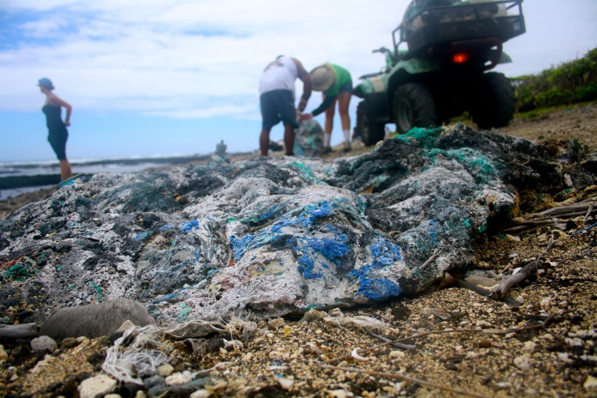 Photo of a gnarled plastic/carbon/rock item in the foreground, with people doing research in the background